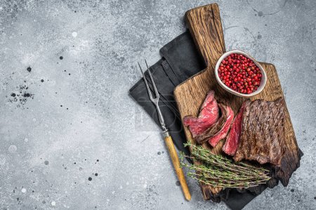 BBQ Grilled Wild Venison steak on wooden board. Gray background. Top view. Copy space.