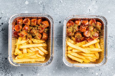 Traditional German currywurst with french fry served take away. Gray background. Top view.
