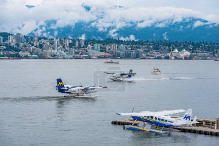 Foto de Vancouver, BC 17 de julio de 2022: Barcos y aviones de mar Harbour Air en Coal Harbour con el horizonte de North Vancouver, BC en el fondo - Imagen libre de derechos
