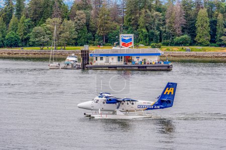 Photo for Vancouver, BC- July 17, 2022: A Twin Otter de Havilland Harbour Air seaplane with the Chevron floating fuel barge in Coal Harbour in Vancouver, British Columbia, Canada - Royalty Free Image
