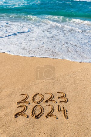 Téléchargez les photos : 2023 2024 written in the sand with wave washing up- New Year concept - en image libre de droit
