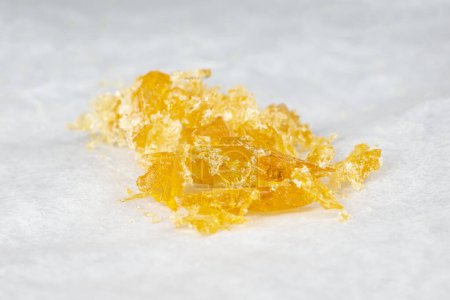 gelb orangefarbene Kristalle aus Cannabiswachs in Nahaufnahme, hoch thc Kleckse Harz.