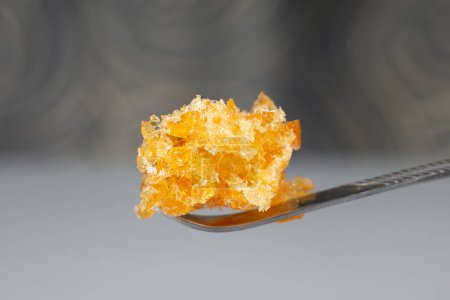 golden cannabis wax crystals on dab stick, high thc marijuana crumble
