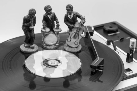 Téléchargez les photos : Figures de musiciens sur un disque vinyle sur un vieux tourne-disque, noir et blanc - en image libre de droit