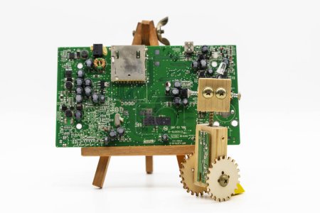 Téléchargez les photos : Petits robots en bois et vis, devant un circuit électronique, isolés sur blanc - en image libre de droit