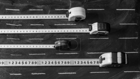 Flexometer ausgebreitet auf einer Tafel mit weißen Kreidestrichen als Straße, in schwarz-weiß
