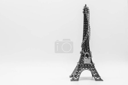 Photo for Miniature Eiffel tower closed with chain and padlock, isolated on white - Royalty Free Image