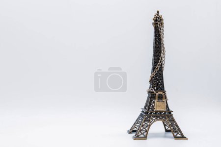 Photo for Miniature Eiffel tower closed with chain and padlock, isolated on white - Royalty Free Image