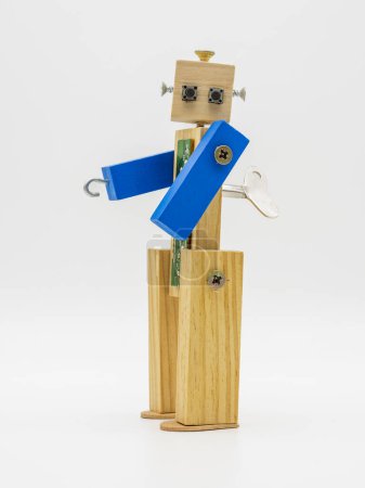Foto de Pequeño robot hecho con madera y tornillos, con llave enrollable, aislado en blanco - Imagen libre de derechos