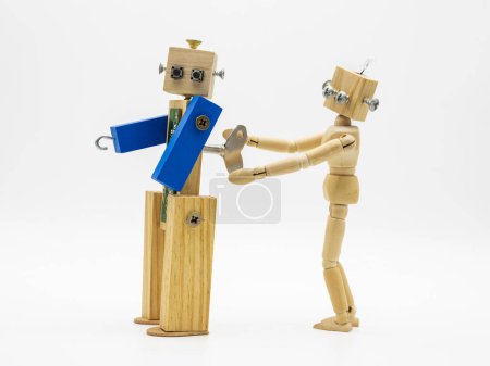 Foto de Pequeños robots hechos con madera y tornillos que giran la llave enrollable, aislados en blanco - Imagen libre de derechos