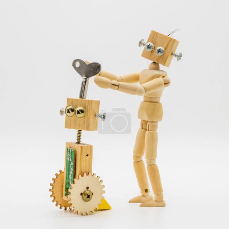Foto de Pequeños robots hechos con madera y tornillos que giran la llave enrollable, aislados en blanco - Imagen libre de derechos