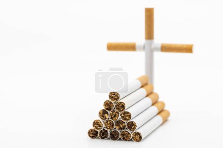Photo for Symbolic grave with cross made with stacked cigarettes of a smoker, isolated on white - Royalty Free Image