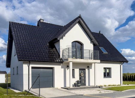Single family house European style, modern architecture. Elegant real estate, facade view. Black rooftiles and white walls.