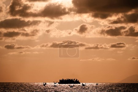 Téléchargez les photos : Réfugiés sur un grand bateau en caoutchouc au milieu de la mer qui ont besoin d'aide. Mer avec des gens dans l'eau demandant de l'aide. Migrants traversant la mer - en image libre de droit