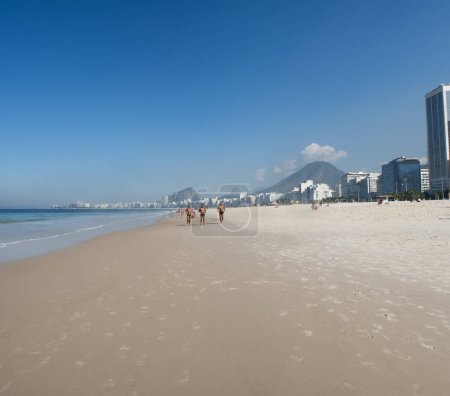 Téléchargez les photos : Rio de Janeiro, Brésil, 06-07-2023 : vue panoramique sur les toits de la ville avec des gratte-ciels, des gens faisant du jogging sur le sable et l'eau cristalline de la plage de Leme, à côté de la plage de Copacabana - en image libre de droit