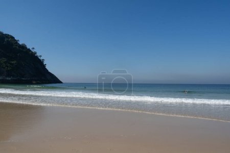 Foto de Río de Janeiro, Brasil, América del Sur, 06-07-2023: Pedra do Leme (Roca de Leme), una colina rocosa llena de vegetación, con la arena y el agua cristalina en la playa de Leme, junto a la playa de Copacababana - Imagen libre de derechos
