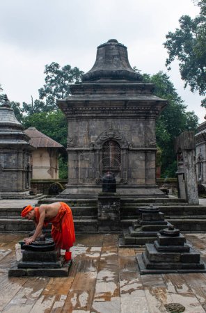 Téléchargez les photos : Katmandou, Népal, 10-03-2023 : Un moine hindou nettoie les autels après des sacrifices d'animaux et des cérémonies de prière, cérémonie de crémation au temple Pashupatinath, célèbre temple hindou dédié à Shiva - en image libre de droit