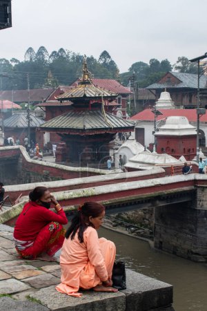 Photo for Kathmandu, Nepal, 10-03-2023: hindu women along the banks of the sacred Bagmati river, cremation ceremony at Pashupatinath Temple, famous Hindu temple dedicated to Shiva, World Heritage Site - Royalty Free Image