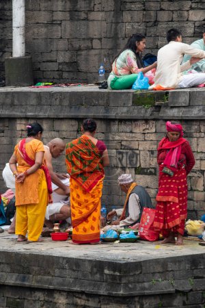 Photo for Kathmandu, Nepal, 10-03-2023: family of the dead praying with a Brahmin and preparing gifts along the sacred Bagmati river, cremation ceremony at Pashupatinath Temple, Hindu temple dedicated to Shiva - Royalty Free Image
