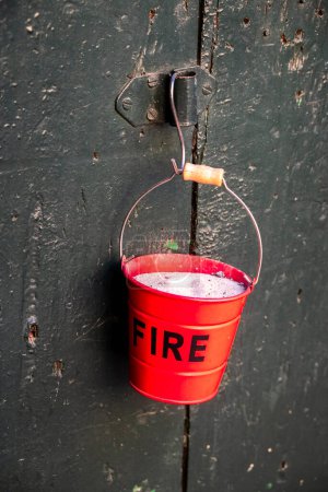 Bucket-shaped cigarette ashtray with the writing: fire, fixed with the handles to an antique wooden door.