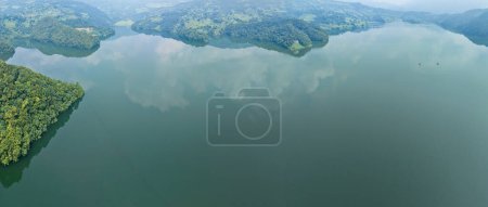 Téléchargez les photos : Vue aérienne du lac Begnas le troisième plus grand lac du Népal. Nature sauvage et arbres avec des maisons entourent le lac, bateaux typiques népalais peuvent être vus dans l'eau - en image libre de droit