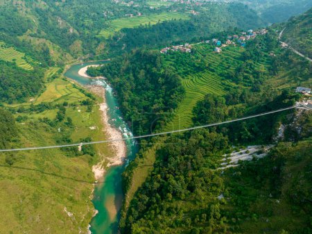 Foto de Vista aérea de un puente colgante tibetano en Nepal es un tipo primitivo de puente en el que la cubierta se encuentra en dos cables paralelos de carga que están anclados en cada extremo. Naturaleza salvaje - Imagen libre de derechos