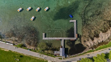 Aerial view of a pier with pedalos and boats and cycle pedestrian path around Annecy lake, France