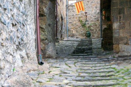 Narrow cobblestone street with stairs and Catalan flag in Bolsena, Italy