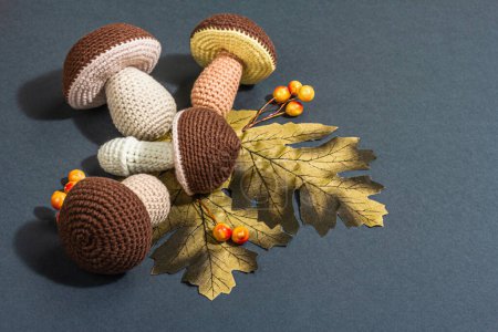 Téléchargez les photos : Fond d'automne traditionnel. Assortiment de champignons tricotés, concept fait main. Lumière dure tendance, ombre foncée, position plate, fond gris mat, espace de copie - en image libre de droit