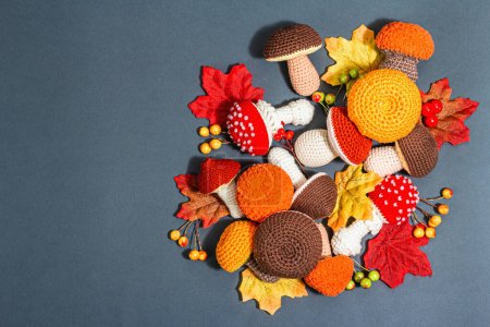 Traditional autumn background. Assorted of different knitted mushrooms, handmade concept. Trendy hard light, dark shadow, flat lay, matte grey background, top view