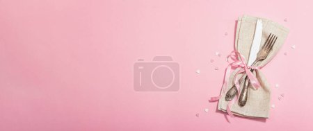 Foto de Mesa romántica en tonos rosados. Cubertería vintage, flores frescas, servilleta de lino. Fondo concepto festivo, plano, luz dura, sombra oscura, vista superior - Imagen libre de derechos