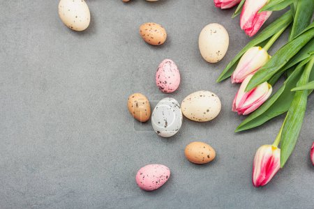Easter flat lay with colorful eggs and tulips. Traditional decor, festive greeting card, holiday concept, gray stone concrete background, top view