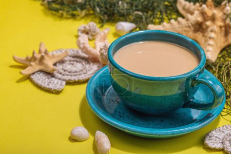 Photo for A cup of coffee in a marine style. Starfish, sea shells, palm leaves. Hard light, dark shadow, bright yellow background, close up - Royalty Free Image