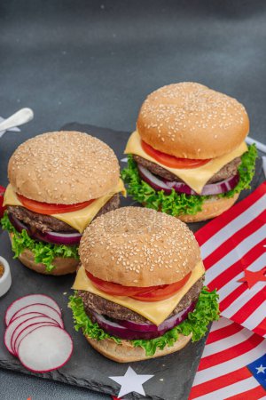 Photo for Homemade burgers. An American classic, traditional food for picnic, party or celebration Independence Day. Sauce, chips, sweet corn. Dark stone concrete background, close up - Royalty Free Image