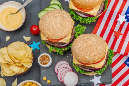 Photo for Homemade burgers. An American classic, traditional food for picnic, party or celebration Independence Day. Sauce, chips, sweet corn. Dark stone concrete background, top view - Royalty Free Image