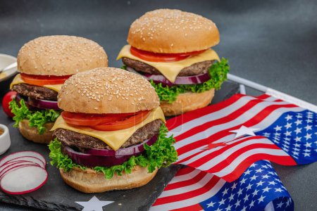 Photo for Homemade burgers. An American classic, traditional food for picnic, party or celebration Independence Day. Sauce, chips, sweet corn. Dark stone concrete background, copy space - Royalty Free Image