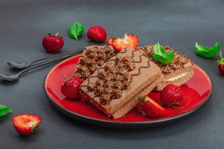 Téléchargez les photos : Délicieux gâteaux au chocolat aux fraises fraîches. Dessert sucré, bonjour concept. Cuisson maison, crème, garniture. Fond en béton de pierre sombre, gros plan - en image libre de droit