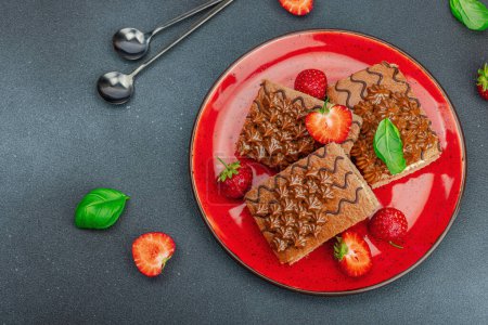 Téléchargez les photos : Délicieux gâteaux au chocolat aux fraises fraîches. Dessert sucré, bonjour concept. Cuisson maison, crème, garniture. Fond en béton pierre sombre, vue de dessus - en image libre de droit