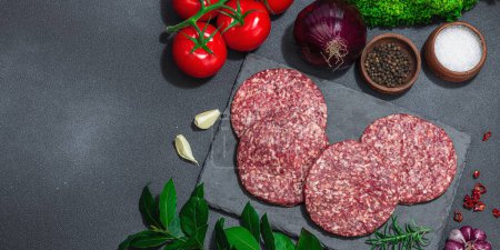 Photo for Raw burger patties. Fresh meat cutlets, spices, vegetables and herbs. Homemade American classic, traditional food for picnic, party or Independence Day. Dark stone concrete background, banner format - Royalty Free Image