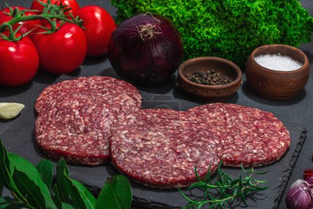 Photo for Raw burger patties. Fresh meat cutlets, spices, vegetables and herbs. Homemade American classic, traditional food for picnic, party or Independence Day. Dark stone concrete background, close up - Royalty Free Image