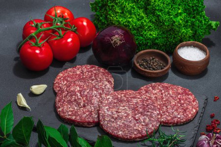 Photo for Raw burger patties. Fresh meat cutlets, spices, vegetables and herbs. Homemade American classic, traditional food for picnic, party or Independence Day. Dark stone concrete background, close up - Royalty Free Image