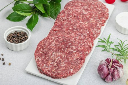 Photo for Raw burger patties. Fresh meat cutlets, spices, vegetables and herbs. Homemade American classic, traditional food for picnic, party or Independence Day. Light stone concrete background, close up - Royalty Free Image