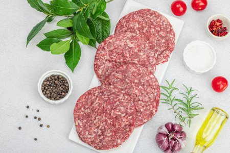 Photo for Raw burger patties. Fresh meat cutlets, spices, vegetables and herbs. Homemade American classic, traditional food for picnic, party or Independence Day. Light stone concrete background, top view - Royalty Free Image