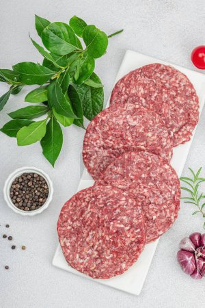 Photo for Raw burger patties. Fresh meat cutlets, spices, vegetables and herbs. Homemade American classic, traditional food for picnic, party or Independence Day. Light stone concrete background, top view - Royalty Free Image