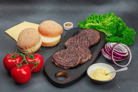 Photo for Grilled burger patties. Hot beef cutlets, buns, vegetables and sauce. Homemade American classic, traditional food for picnic, party or Independence Day. Dark stone concrete background, copy space - Royalty Free Image