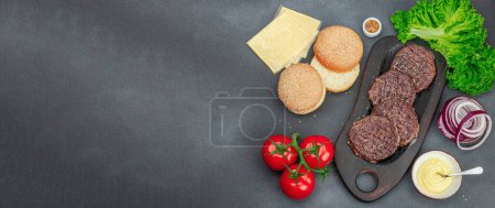 Photo for Grilled burger patties. Hot beef cutlets, buns, vegetables and sauce. Homemade American classic, traditional food for picnic, party or Independence Day. Dark stone concrete background, banner format - Royalty Free Image