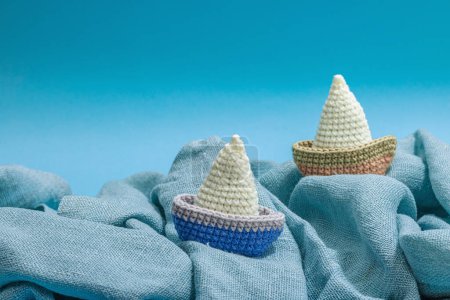 Photo for Handmade marine concept. Crocheted boats, nautical style, traditional sea decor. Hard light, dark shadow, trendy blue background, copy space - Royalty Free Image