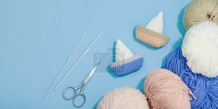 Photo for Handmade marine concept. Crocheted boats, nautical style, traditional sea decor. Hard light, dark shadow, trendy blue background, banner format - Royalty Free Image