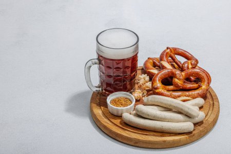 Photo for Traditional Oktoberfest set. Pretzels, beer, weisswurst with mustard. German festival food concept. Trendy hard light, dark shadow, light stone concrete background, copy space - Royalty Free Image
