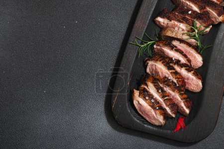Photo for Fried duck breast with fresh orange and ginger, ready to eat food. Domestic tasty cuisine, poultry meat fillet. Dark stone concrete background, top view - Royalty Free Image